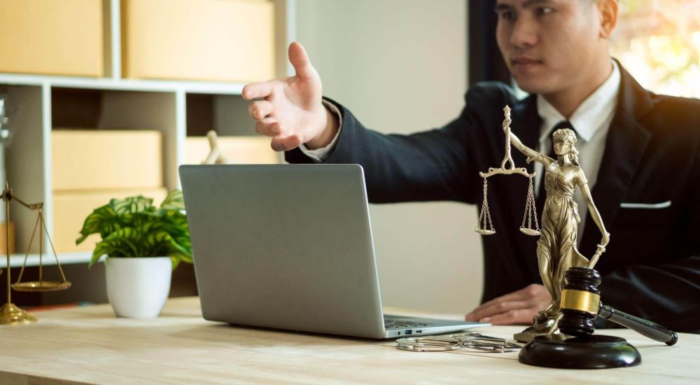 a man in a suit pointing at a statue of lady justice