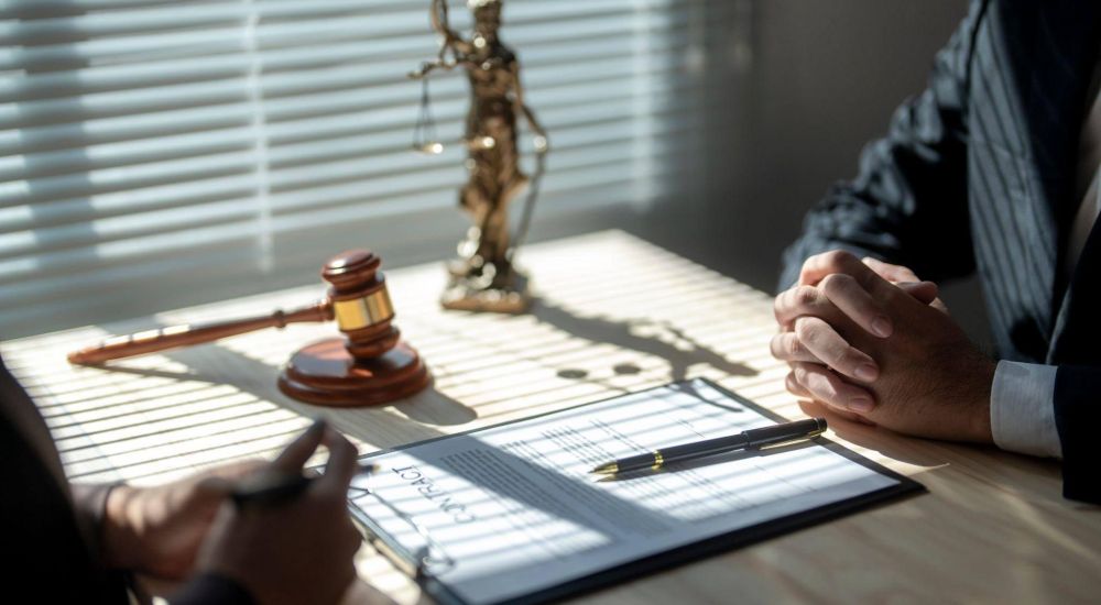 two people sitting at a table with a pen and paper in what appears to be a judge's office