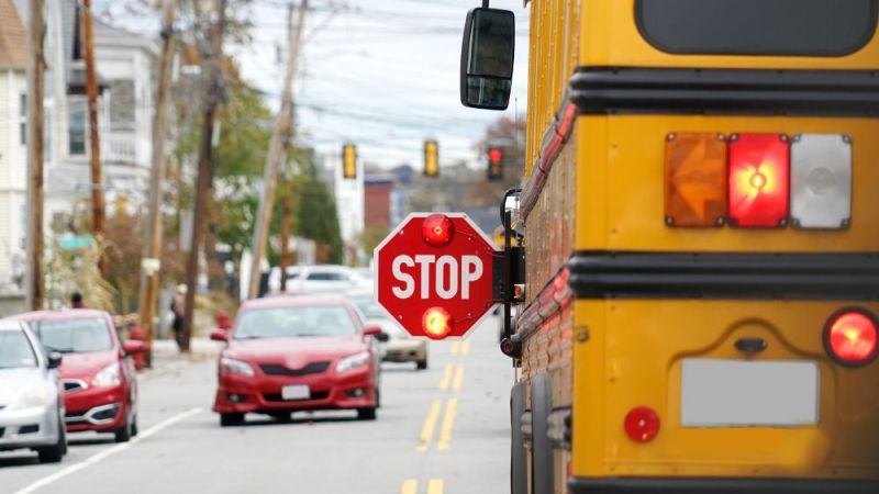 school bus with stop sign flashing on the street