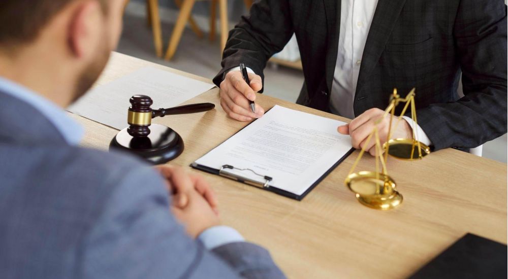 a man in a suit sitting at a desk signing a paper
