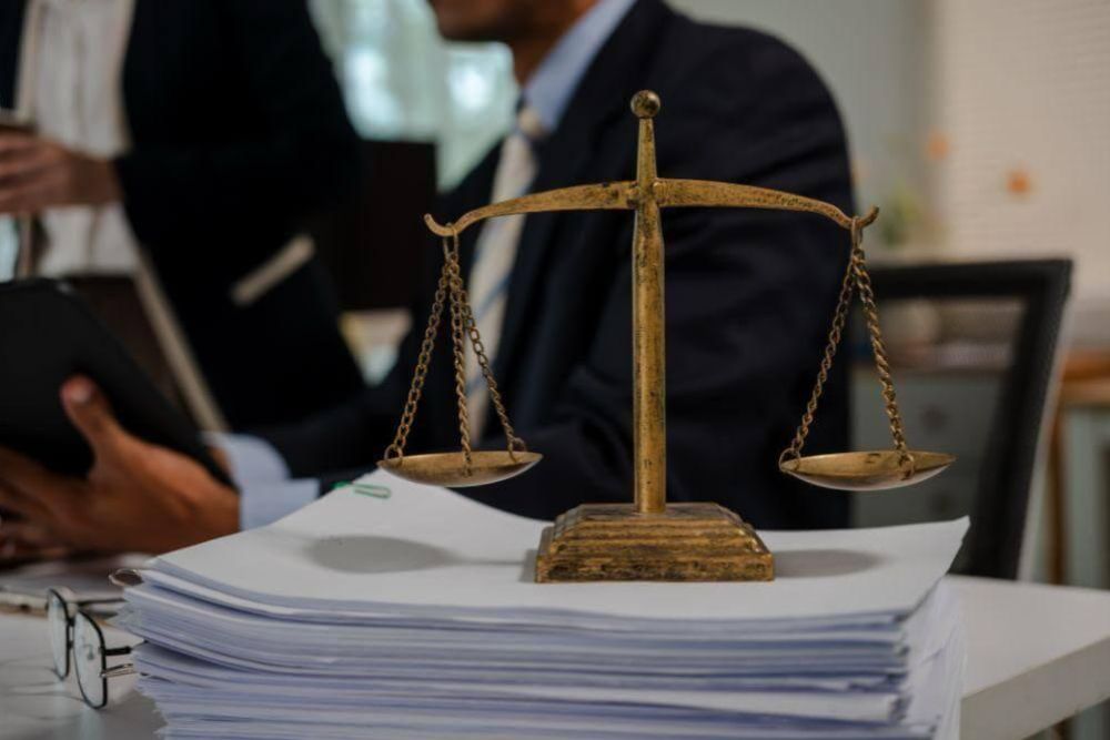 Gold balance scales atop a stack of documents in an office, symbolizing justice or legal balance in work.