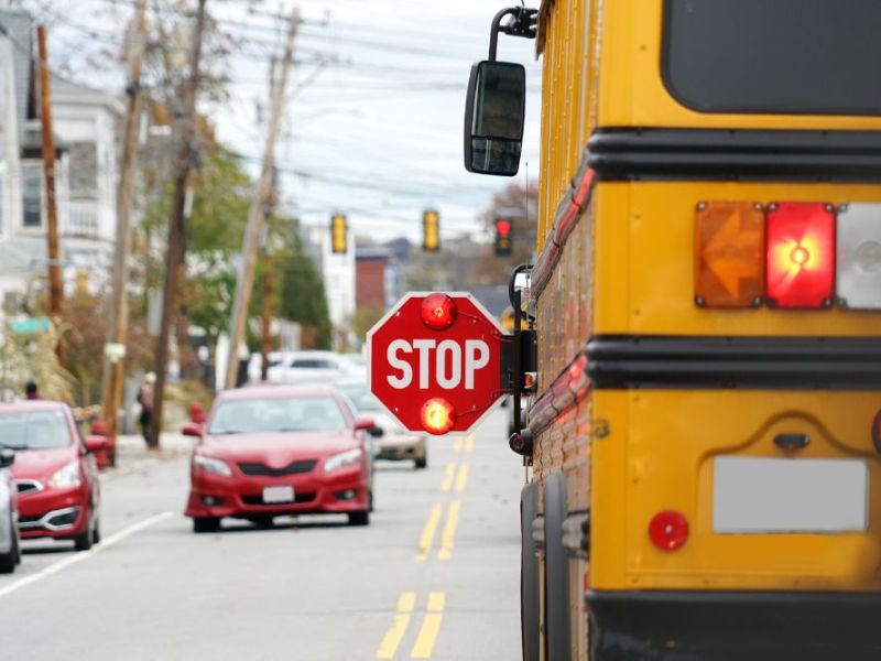 school bus with stop sign flashing on the street