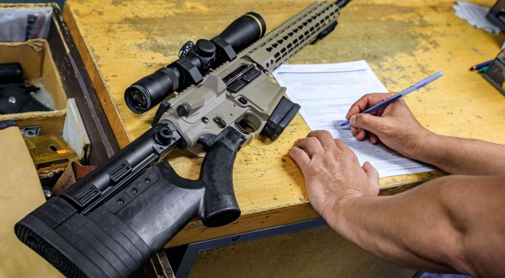 Person writing with a gun nearby