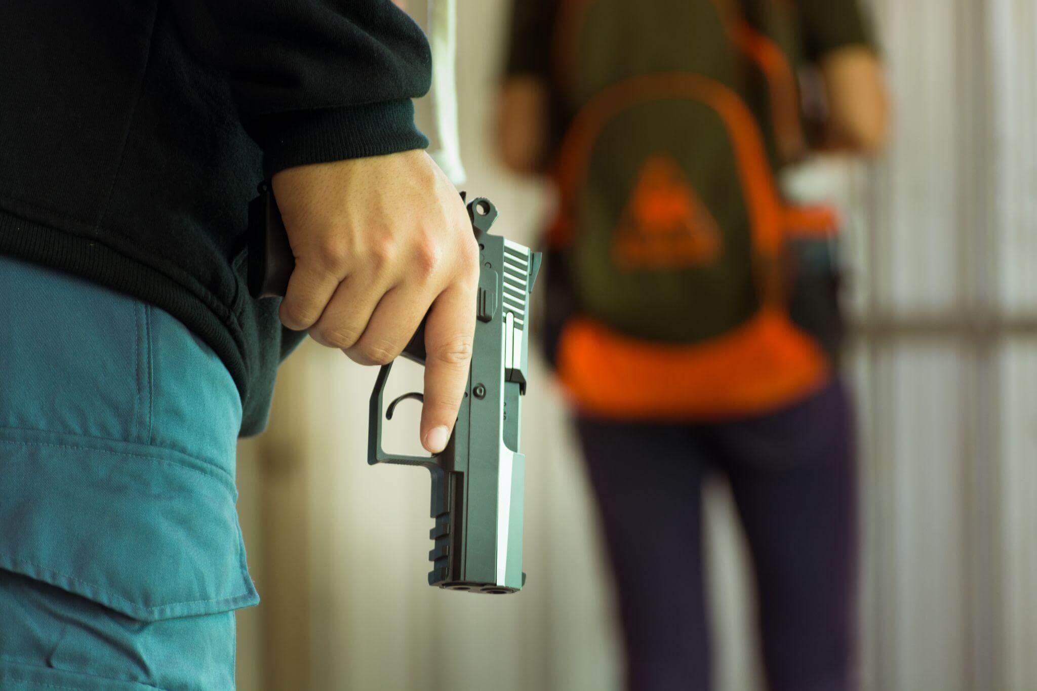 a person holding a gun in front of another person who is walking away