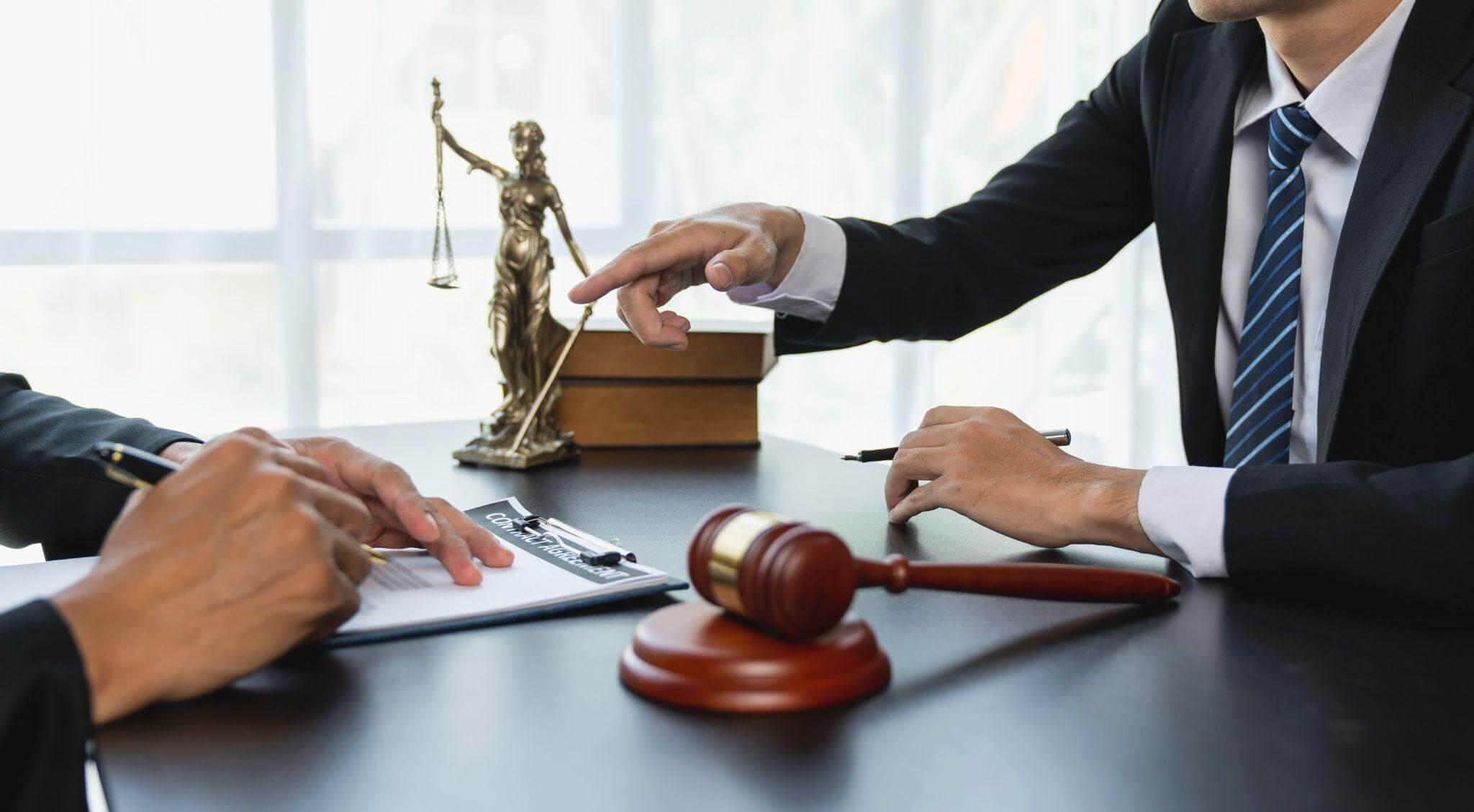 two people sitting at a table in front of a statue and reviewing documents in a judge's office