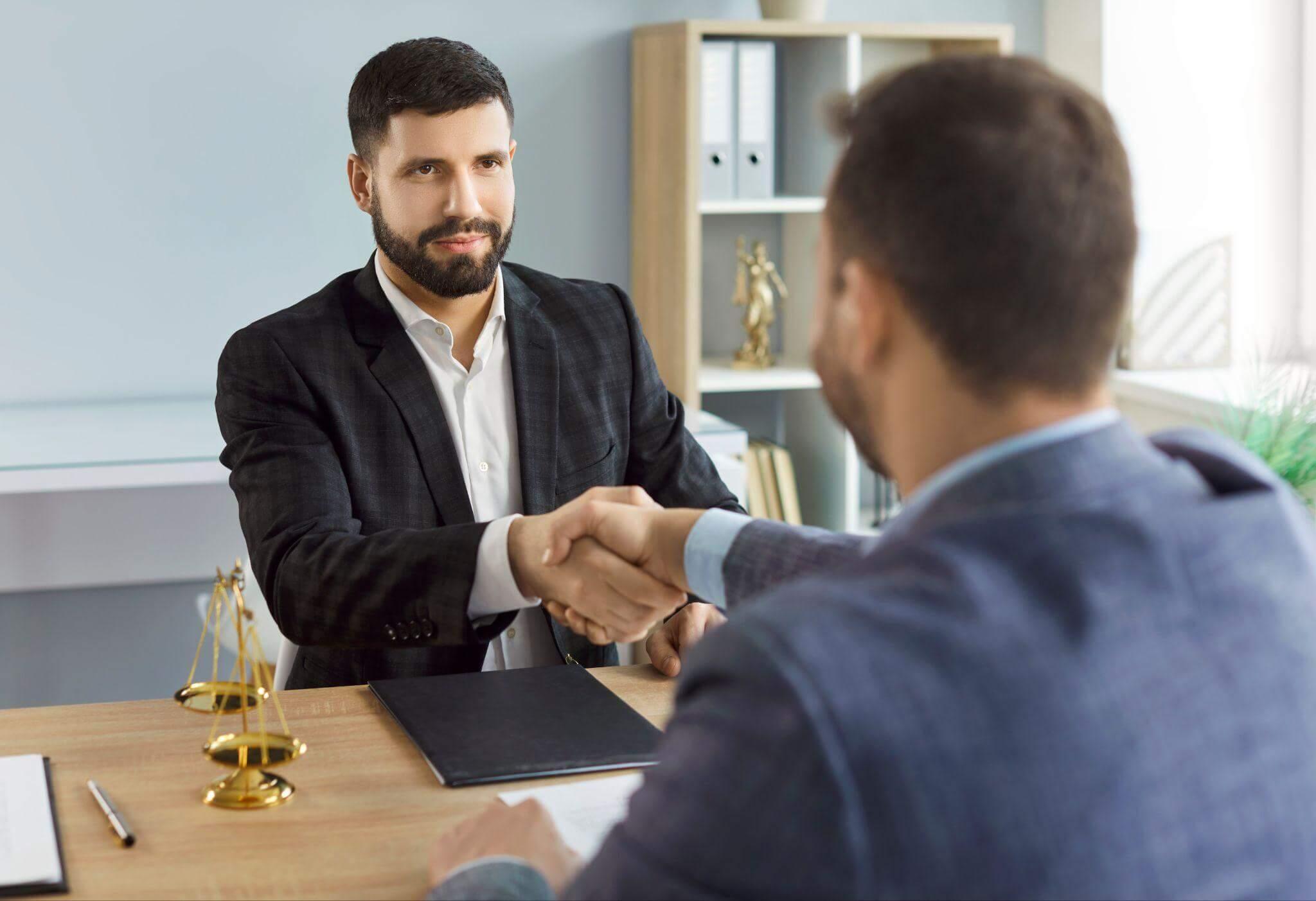 a man shaking hands with another man sitting at a desk