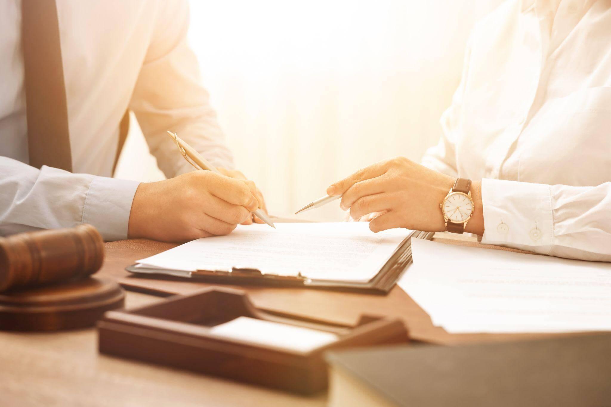 two people sitting at a table signing papers